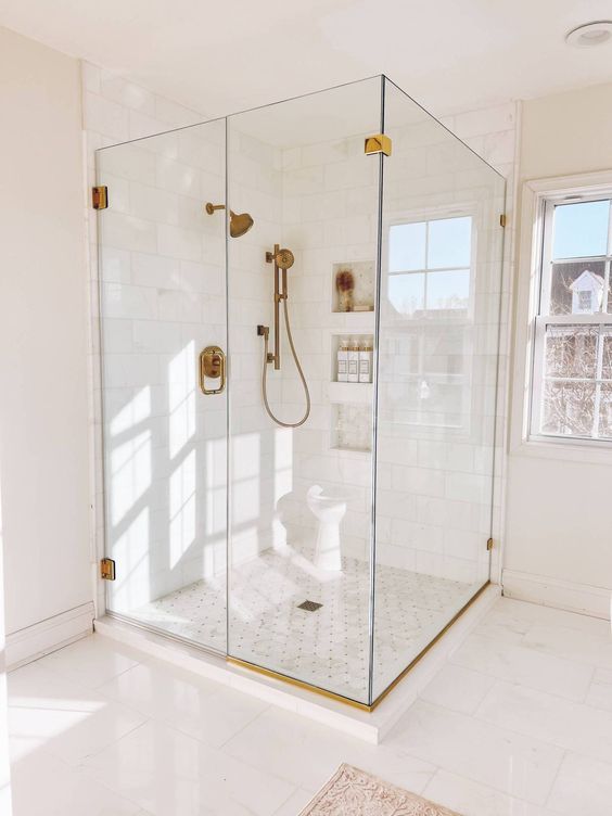 Neutral Bathroom with Glass Enclosures and Brass Fixtures