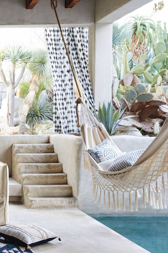 Boho desert outdoor space with cacti, a hammock, and a poolside terrace
