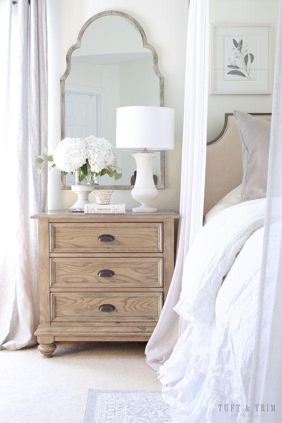 Bedroom Featuring Light Curtains and a Mirror Behind the Nightstand